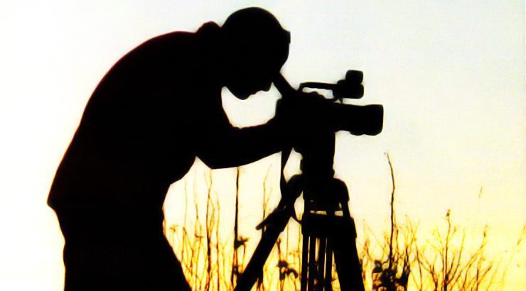 A documentarian peering through the viewfinder of his camera